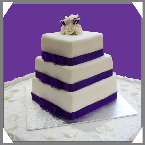  white sugarcrafted roses and purple ribbons to accentuate wedding cakes