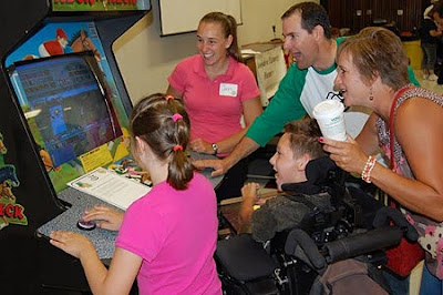 Image of a switch adapted Neck-n-Neck arcade game for up to six players each using a single switch. Family look to be having huge fun.
