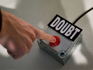 Image of a man's hand reaching out to press a red push button, above which is the word 'Doubt'.
