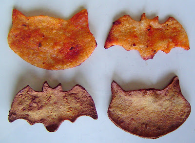 a cat and bat shaped homemade tortilla chip dyed with soy sauce and tomato sauce then baked to show the finished product