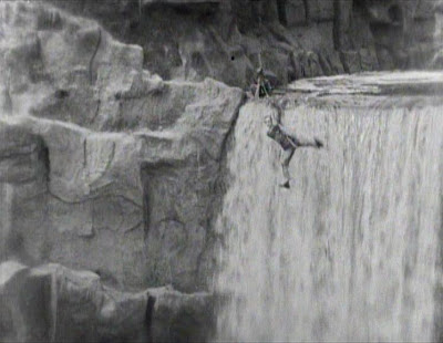 Dude is straight up hanging from a log over a waterfall.
