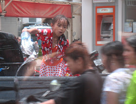3 people on a moped about to be OWNED by the small girl throwing water