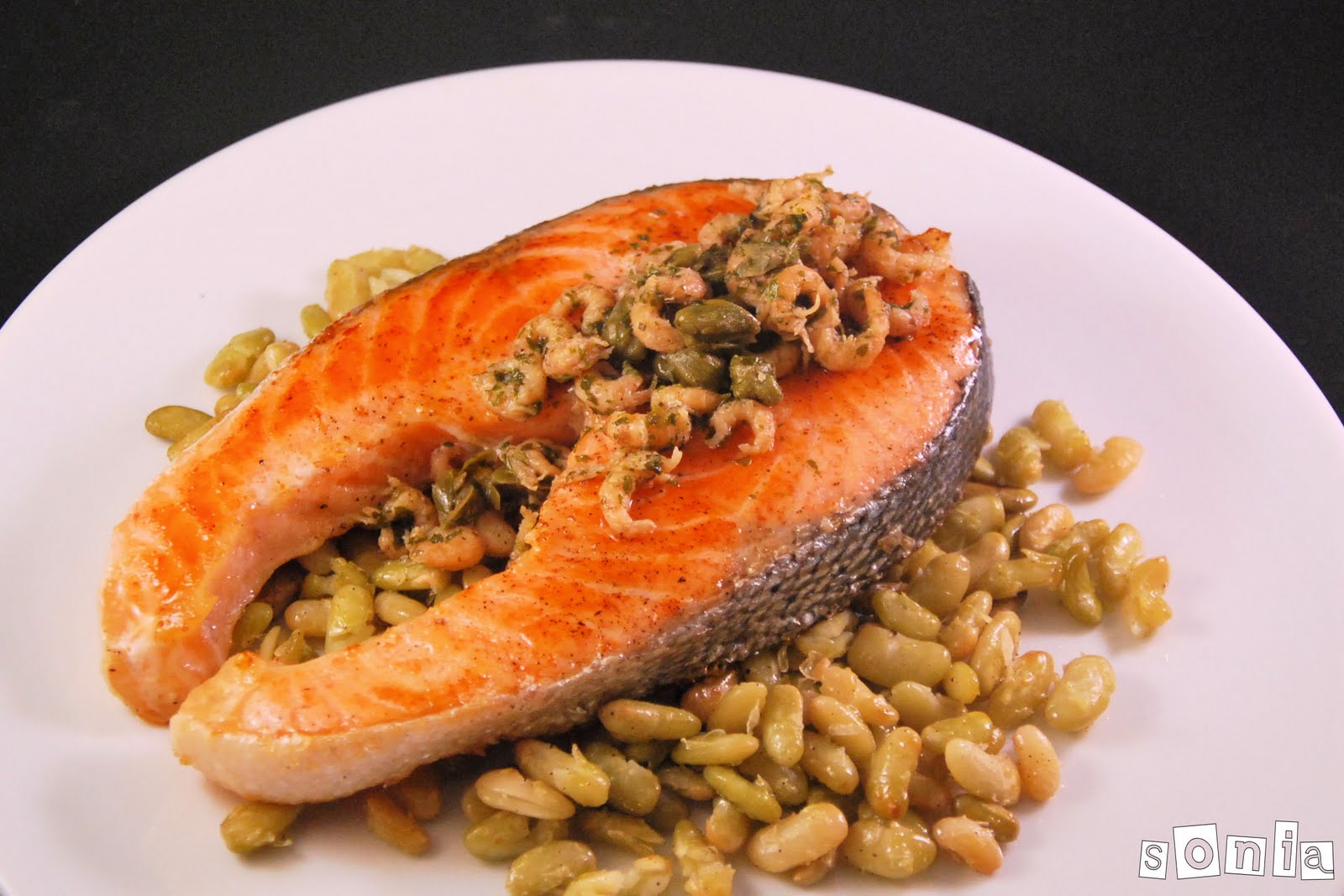 Salmón con gambitas y alcaparras sobre un lecho de verdinas