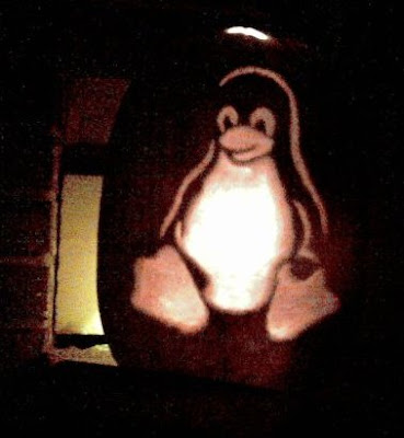 Tux says hello! picture of a pumpkin with a carving of Tux the Linux mascot on the front glowing