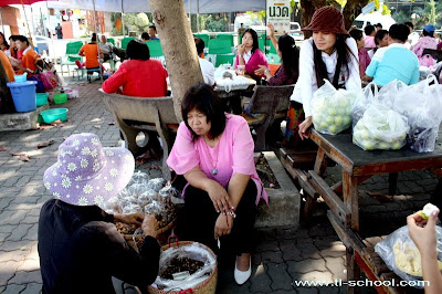 ครูอมร กำลังช่วยแม่ค้าขายถั่วปากอ้า บริเวณตลาดด่านท่าขี้เหล็ก