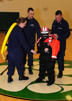 Petty Officer 3rd Class Ryan Levine, Master Chief Petty Officer Aaron Zimmer and Petty Officer 1st Class John Curtis, from Coast Guard Station Toledo, Ohio, help a student volunteer from Margaretta Elementary School dress out in Coast Guard ice rescue gear, Dec. 15, 2010. U.S. Coast Guard photo by Petty Officer 3rd Class George Degener