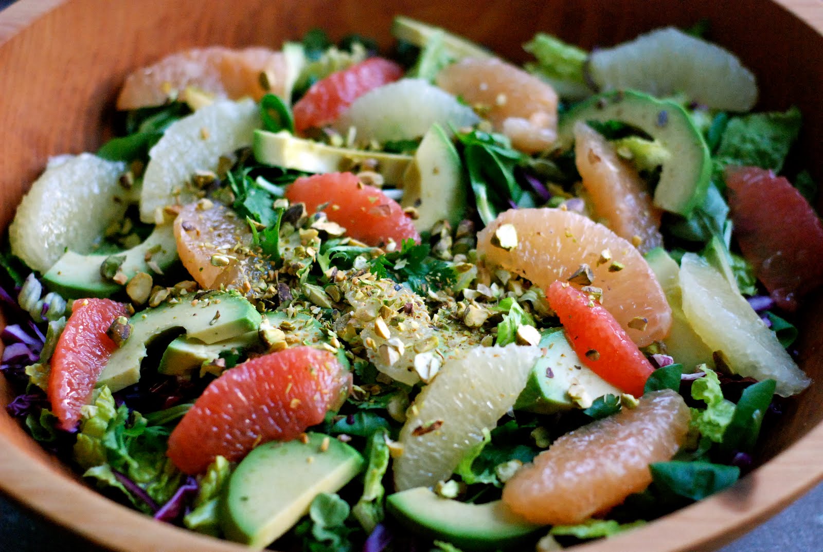 cup and table salad with mixed greens grapefruit, avocado and pistachios