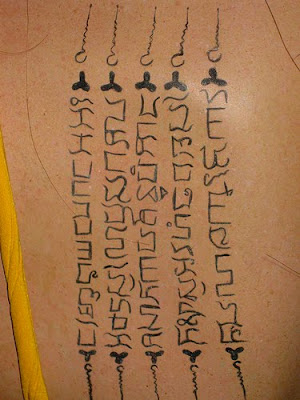 Angelina Jolie Black Cross tattoo. Gothic letter tattoo between her shoulder