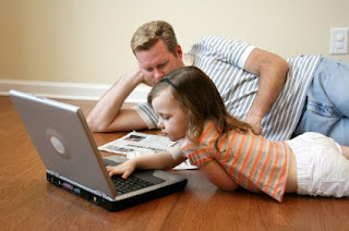 Kids don't read newspapers... but they do decide where the family should go on holiday Dad and daughter reading newspaper and laptop