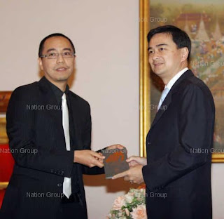 Apichatpong hands an autographed Uncle Boonmee press kit to thai Prime Minister Abihist Vejjajiva.