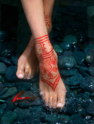 Beautiful red henna tattoo on woman foot.