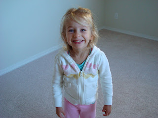 Young girl smiling in room wearing white zip up jacket