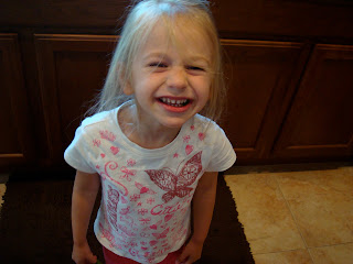 Young girl standing in kitchen squinting and smiling