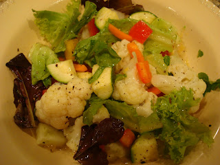 Mixed green salad with vegetables topped with orange vinaigrette  