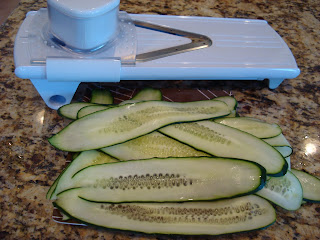 White mandolin with thinly sliced cucumbers