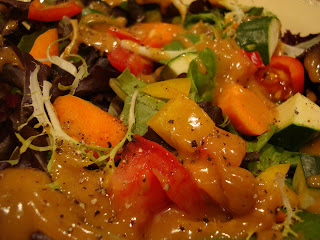 Bowl of mixed greens with diced vegetables with Homemade Peanut Sauce up close