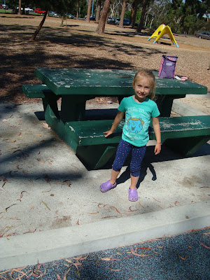 Child standing next to picnic table smiling