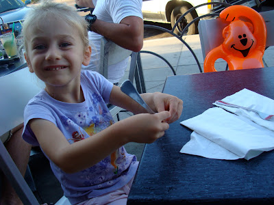 Young girl sitting at table playing with silverware