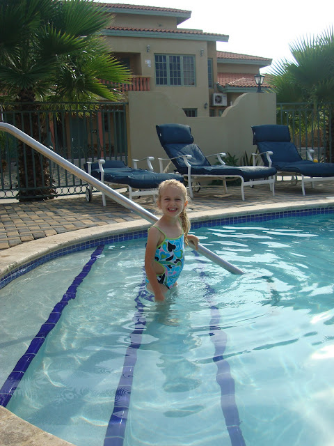 Young girl in steps in pool at complex