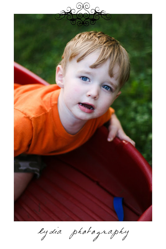 Little boy in a red wagon at lifestyle kids portraits on a farm in Indiana, Pennsylvania