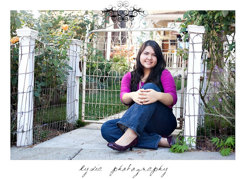 Senior girl sitting infront of a white gate at American Christian Academy senior lifestyle portraits in Grass Valley, California