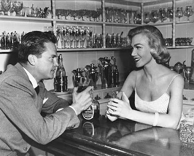 Marian Carr shares a beverage with Ralph Meeker in Kiss Me Deadly.