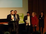 Carles Palau, recogiendo el premio. Al fondo, Samuel Sebatián con el premio en sus manos