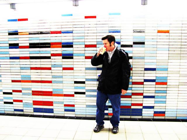 A cold and tired traveler having some late night coffee in a Dutch train station.