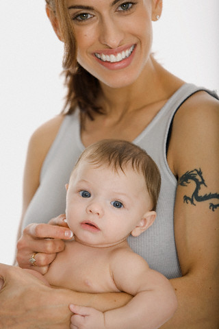 A woman with her baby having black small dragon tattoo on her arm.