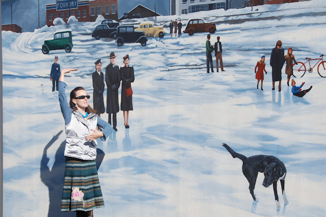 WOman in front of an ice skating mural pretending to skate