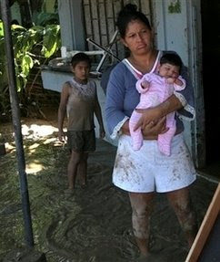 Jackeline Chacon holds her 28 day old baby Surayi, as her son looks on in their flooded home after heavy rains from Tropical Storm Alma caused flooding in Parrita, Costa Rica, Friday, May 30, 2008. Tropical Storm Alma weakened to a depression and swept across Central America on Friday, dumping rain and leaving flooded coastal towns in its wake. (AP Photo/Kent Gilbert)