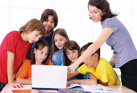 Photo: A group of children with their teacher around a single laptop