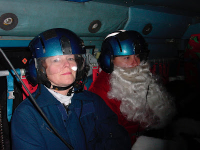 Kodiak, AK (Dec. 5)--Santa Claus and his helper, Kathy Gundersen, relax aboard a Coast Guard helicopter on their way to Karluk. Santa and his staff traveled on Coast Guard helicopters to eight remote villages on Kodiak Island. USCG photo by PAC Marshalena Delaney