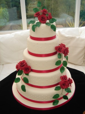 Classic and elegant wedding cake with red ribbons and red roses