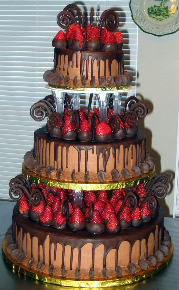 Three tier wedding cake dripping in dark chocolate with strawberries