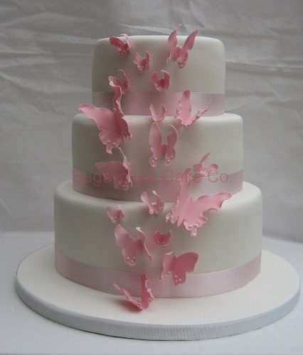 Three tier round pink wedding cake separated by columns and decorated with 