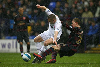 Gary Cahill of Bolton is tackled by Nicklas Bendtner of Arsenal.