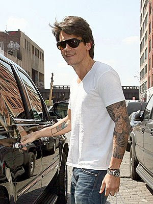 John Mayer wearing white t-shirt while showing some tattoo sleevage.