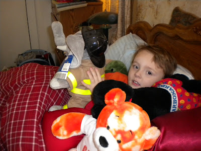 4 year old Brian in bed surrounded by pillows and stuffed animals