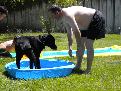 Dagan standing in the pool with John next to him playing