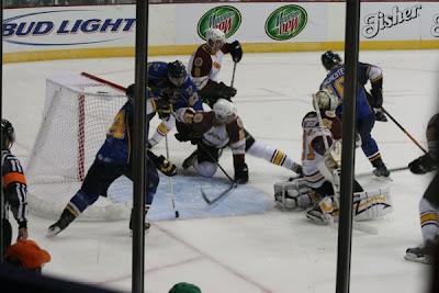 Credit:Jane Rickard,Lavallee extends his leg behind Pavalec, Machacek works backs into the Riverman on point and a second Peoria player moves in to score.