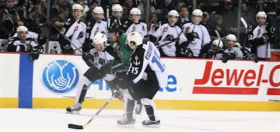 Credit:Jane Rickard, Chad Denny fights his way to the puck between two Milwaukee players