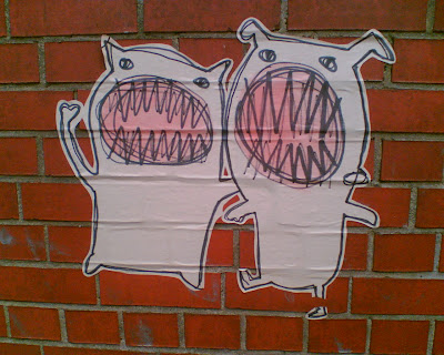 sticker graffiti of two monsters with wide open mouths full of very sharp teeth
