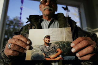 Guy Fulcher holds a photo of his son Brian Sessoms.