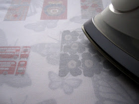 Iron pressing the wrong side of a piece of printed fabric.
