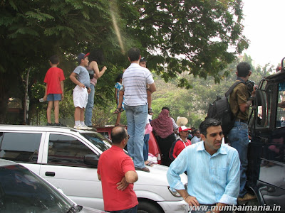 the crowd standing on cars to get a peek of the high end cars