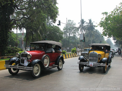 two similar vintage cars driving side by side