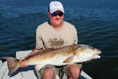 fisherman siting with big redfish