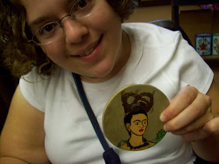 Sarah holding a coaster painted with a picture of Frida Kahlo