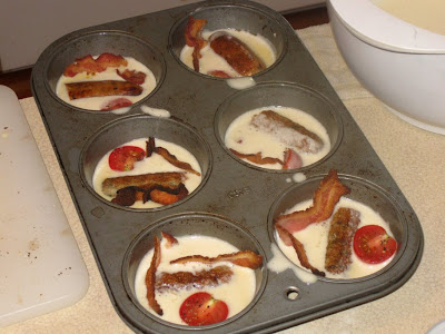 Muffin tin filled with popover batter, bacon, sausage and tomato
